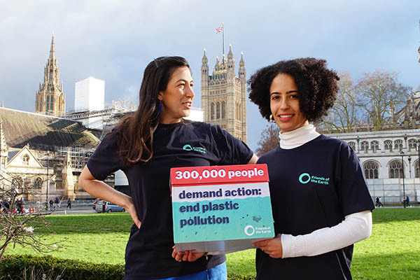 A photo of two people holding a placard that says '300,000 people demand action: end plastic pollution' 