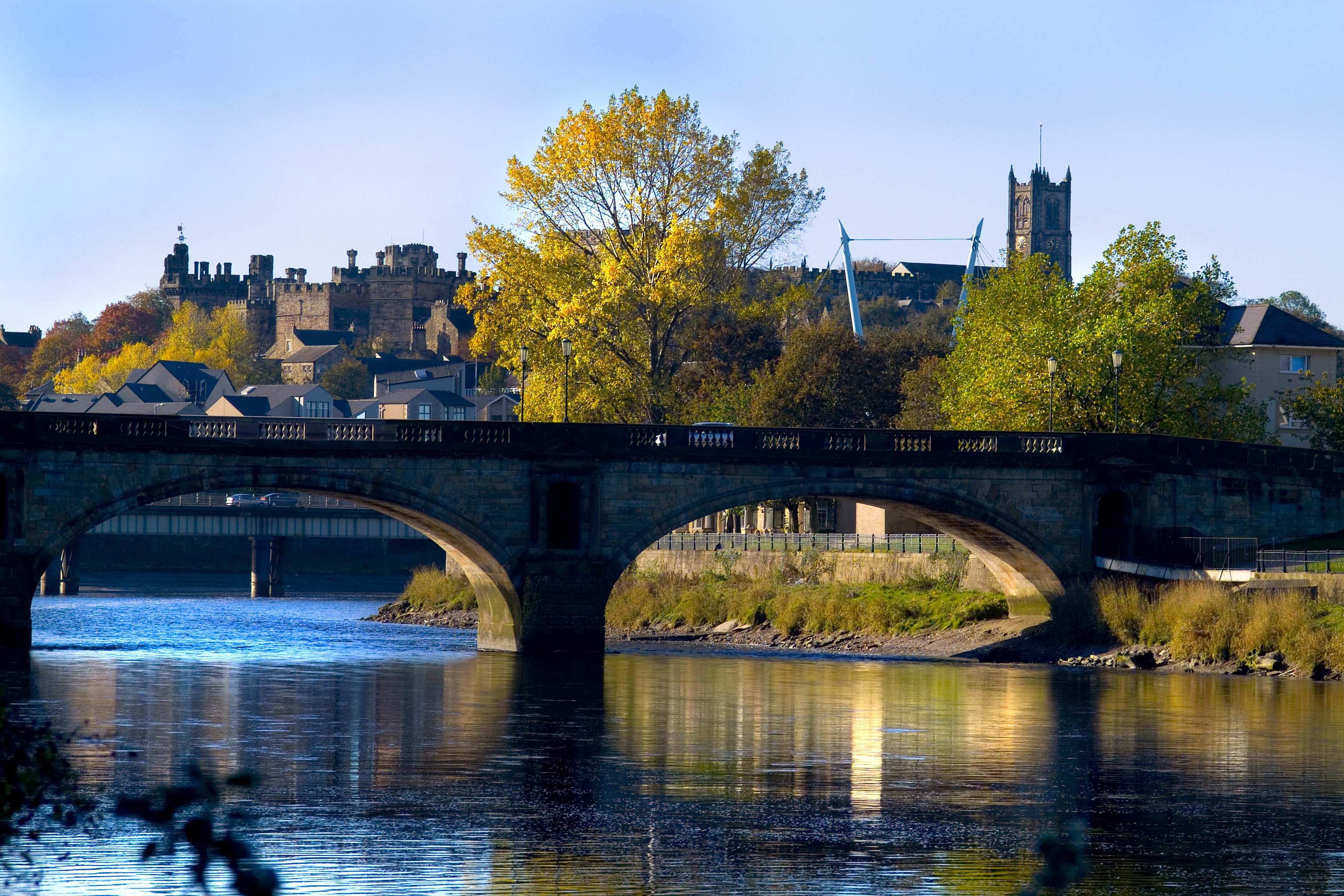 A landscape of Lancaster city with a river and bridge in the foreground
