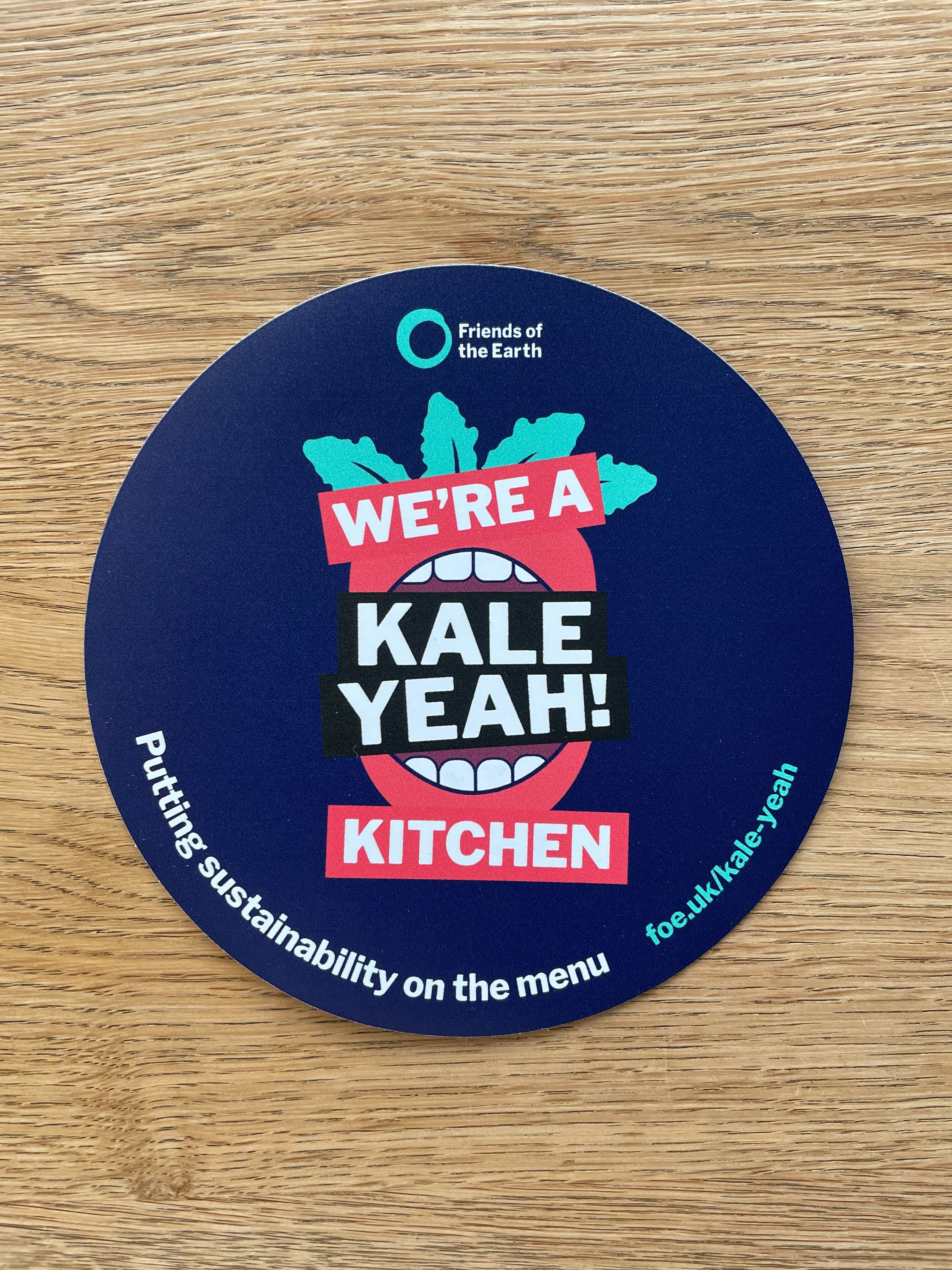 Circular window sticker that says "We're a Kale Yeah! Kitchen"