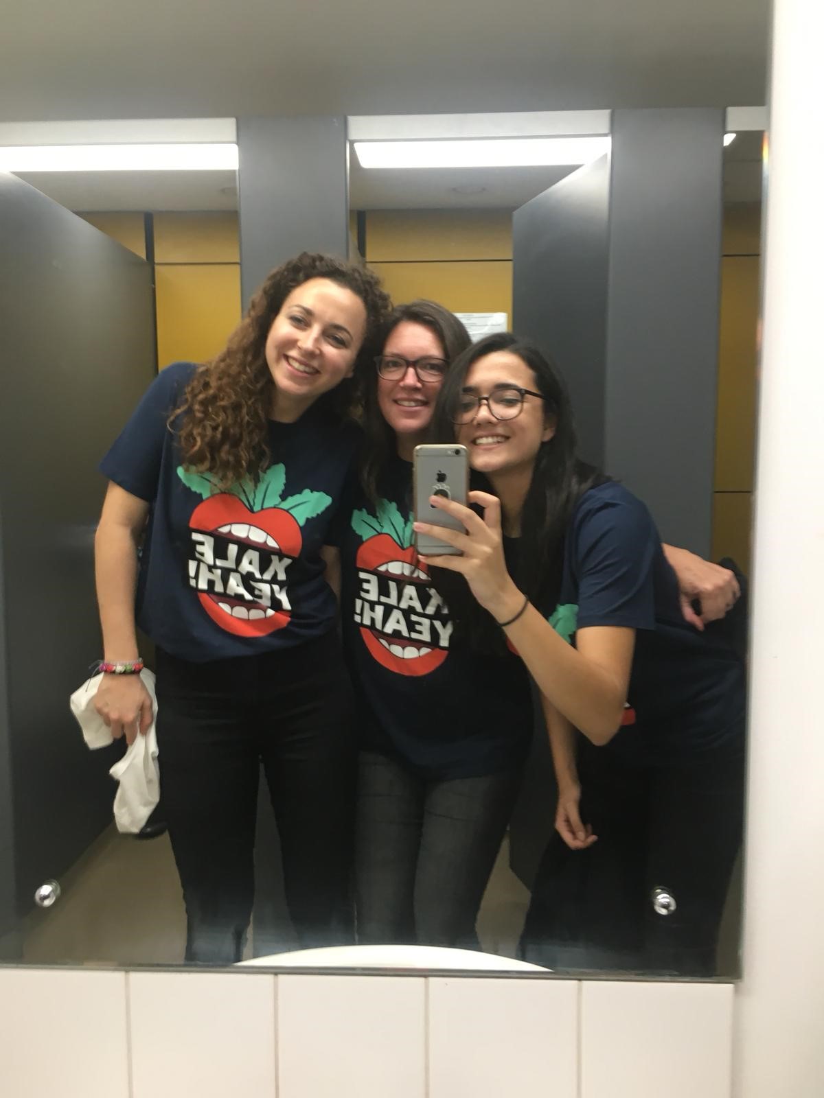 Three women wearing Kale Yeah! t-shirts and photographing themselves in a bathroom mirror 