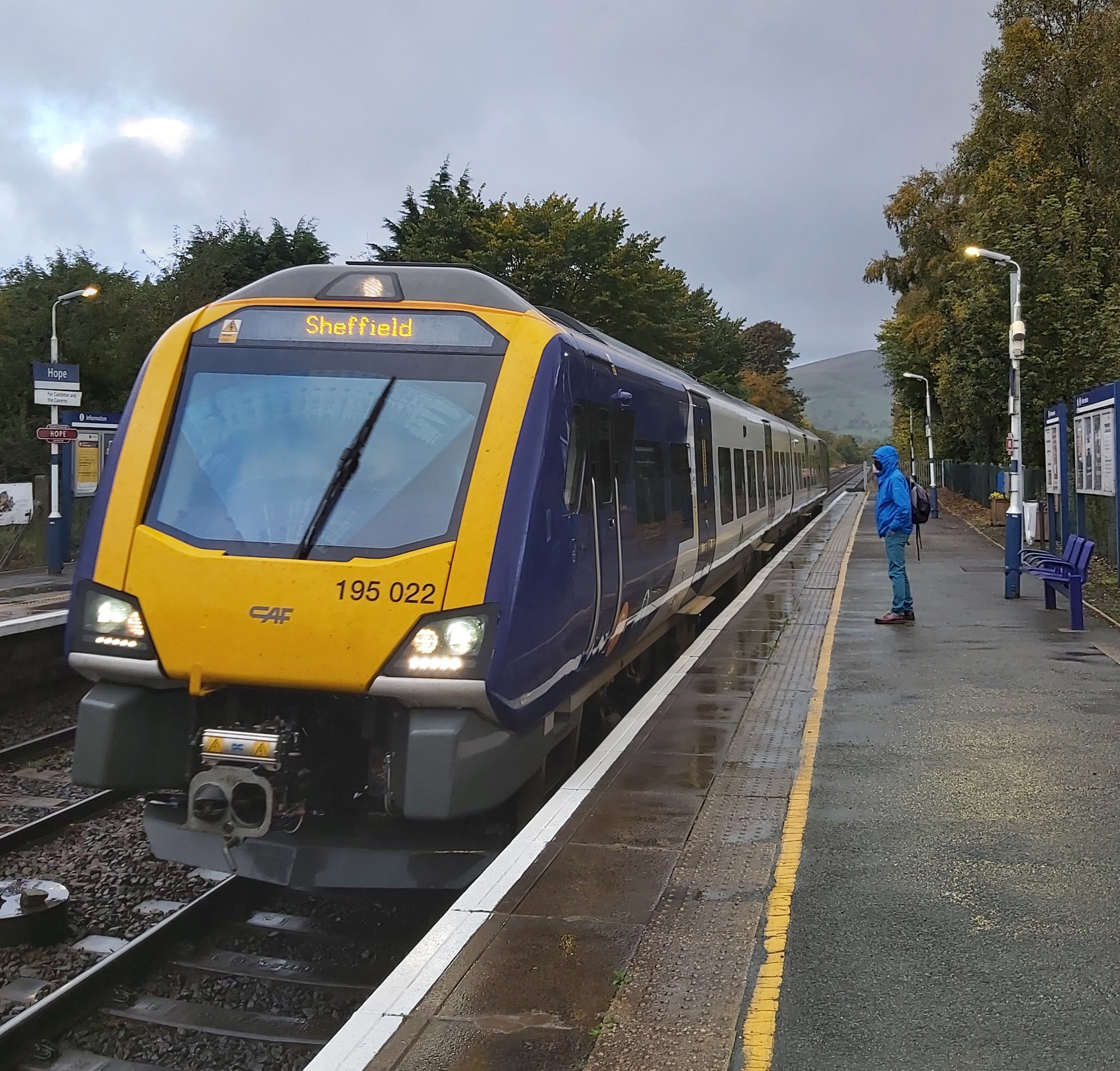 A train station platform with a train to Sheffield pulled in and a person about to board