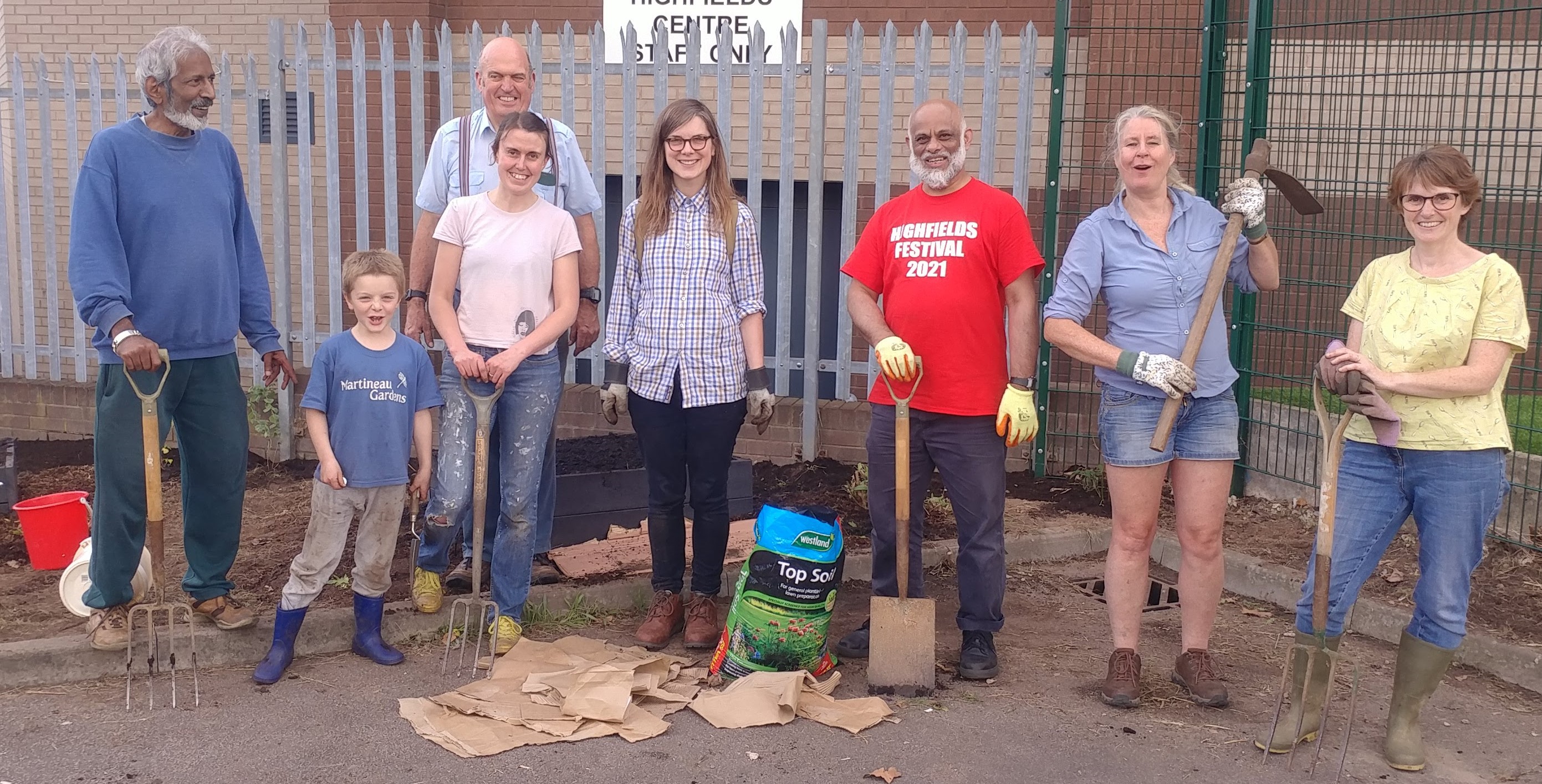 Group members facing the camera, looking happy with gardening equipment 