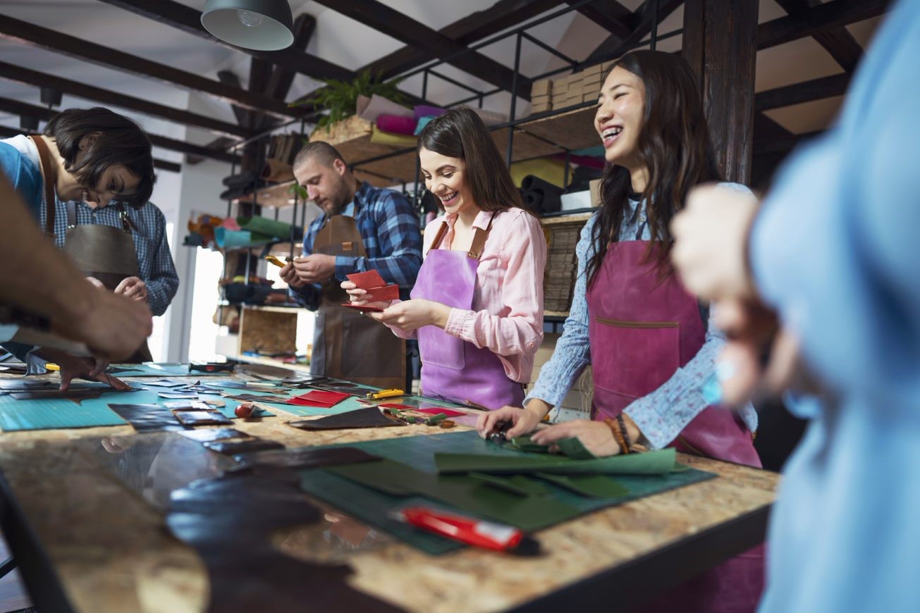 Group of happy people stood around a table and crafting with paper