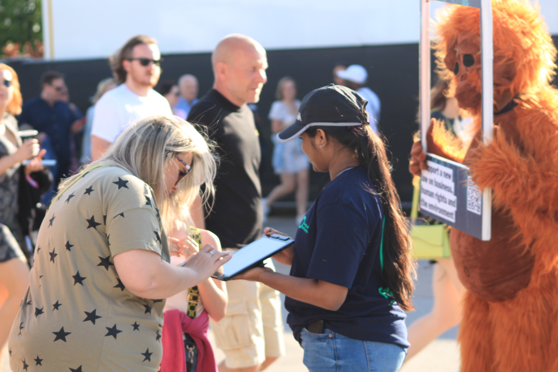 A person signing a petition with someone else dressed in an orangutan costume