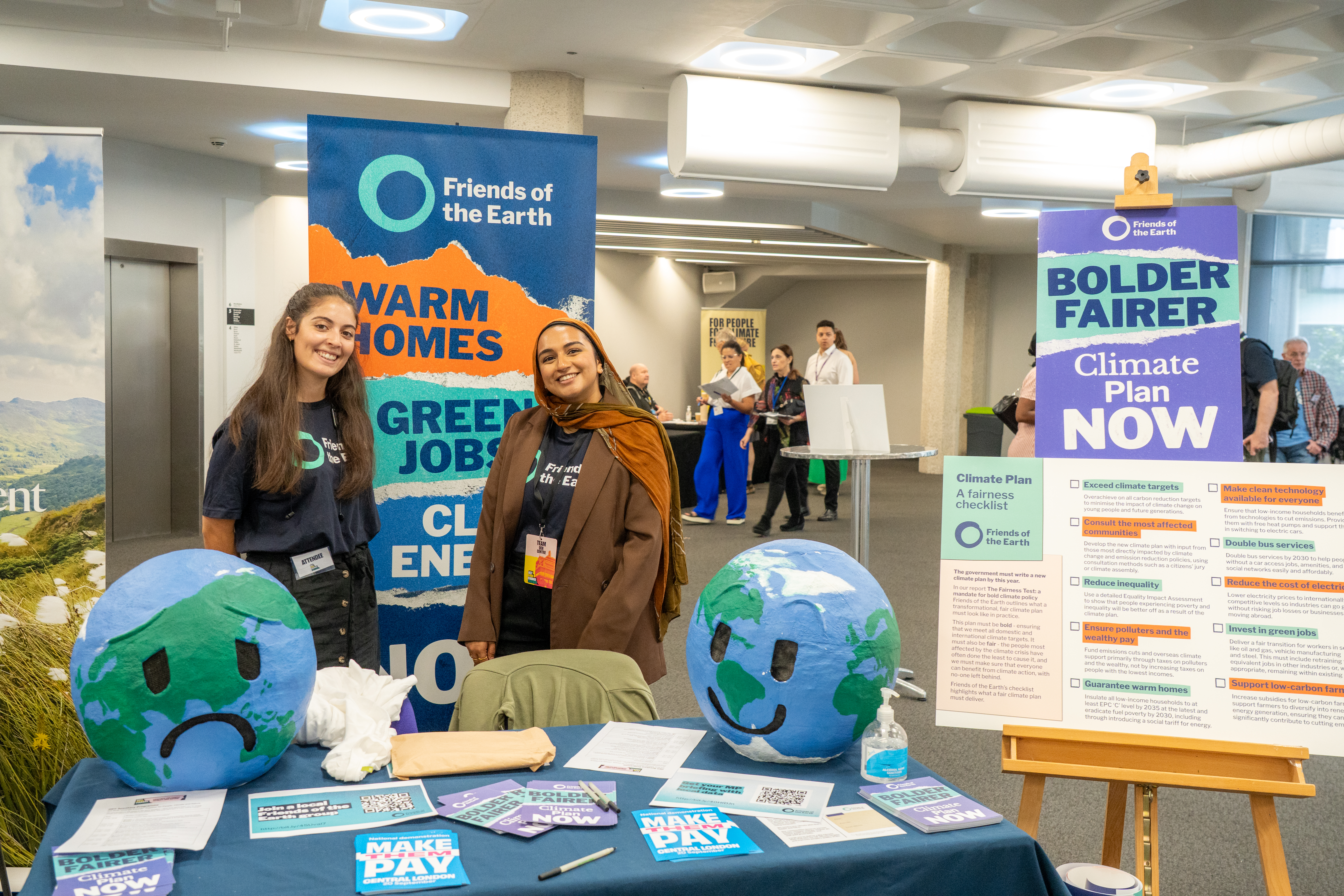 2 Friends of the Earth staff members at a stall demanding a bold climate plan