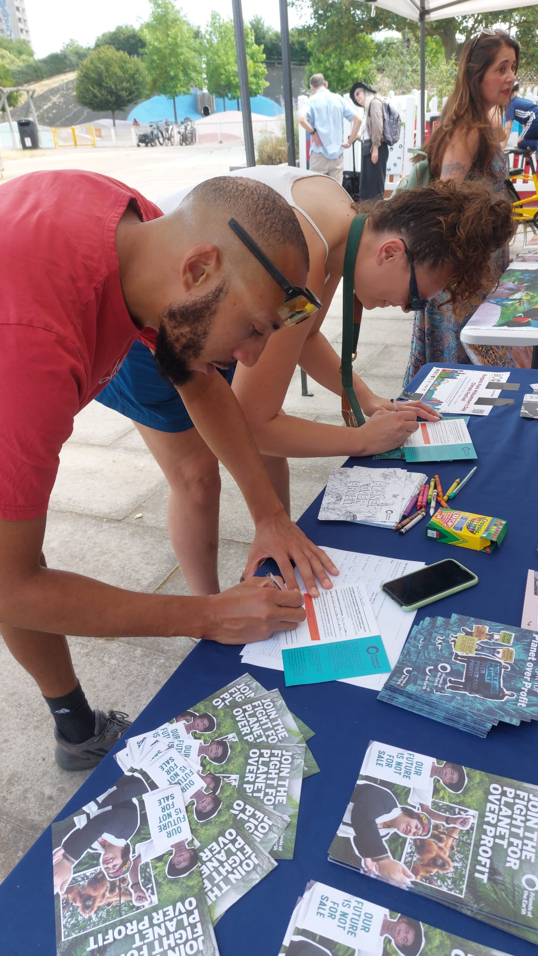 People taking part in a written activity at a Friends of the Earth stall