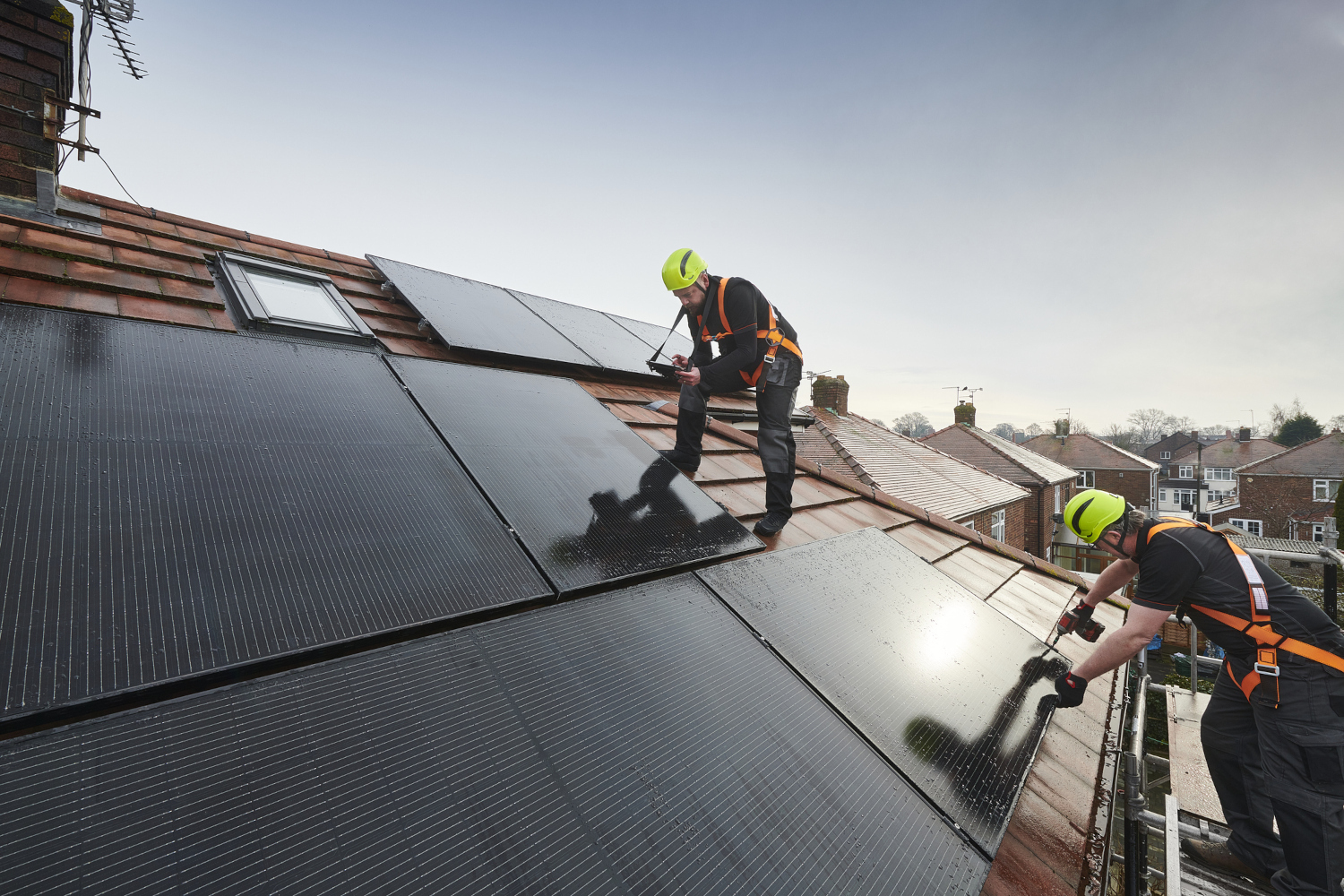 A man installing solar panels on a home roof A man installing solar panels on a home roof