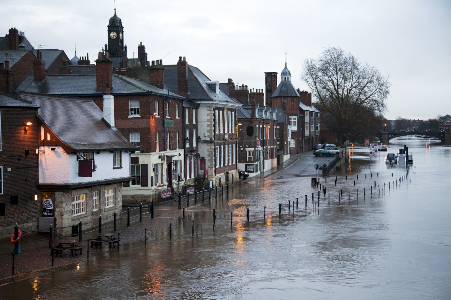 River in flood breaks its banks, covers the road and pavement, and floods the basement of the local pub York Floods