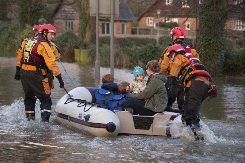 Children and woman on a small boat being rescued form flooding