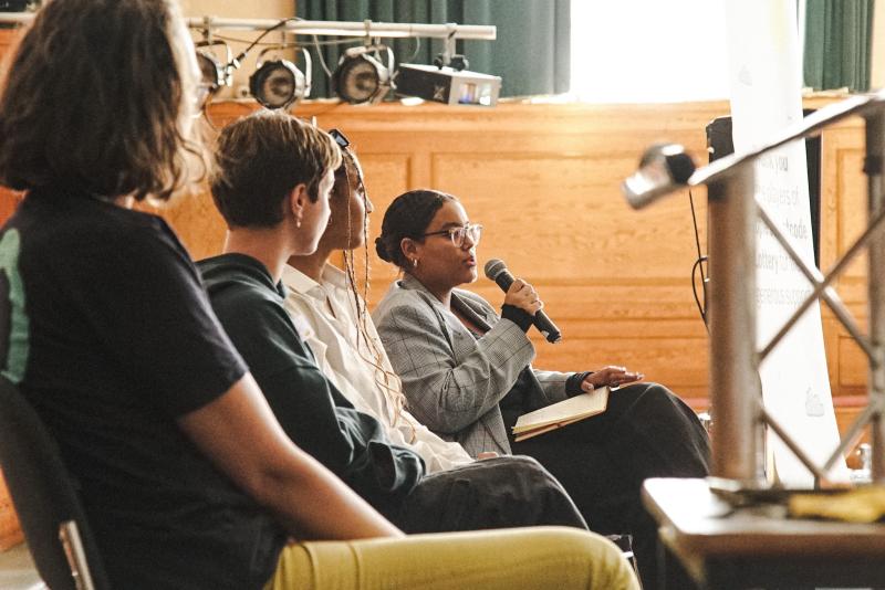 A group of people on stage, one is speaking on a mic 