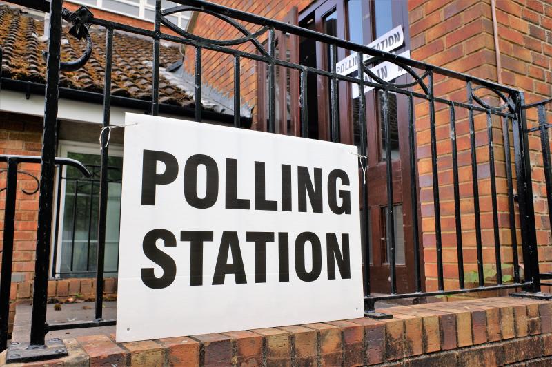 A polling station sign attached to some railings outside a building