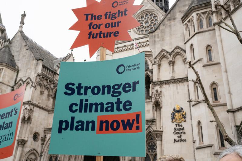 A protest banner which reads "Stronger climate plan now!" held outside of the Royal Courts of Justice