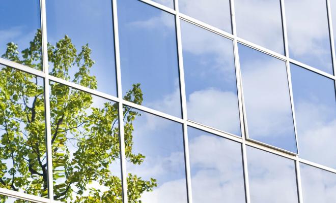 Glass building reflecting tree and sky