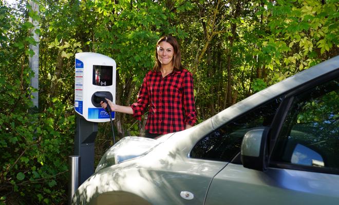 Woman plugs in a charger for an electric car