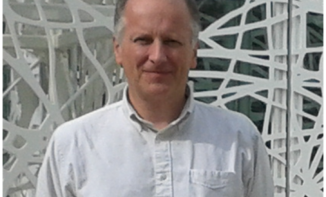 A man looking straight at the camera wearing a white shirt