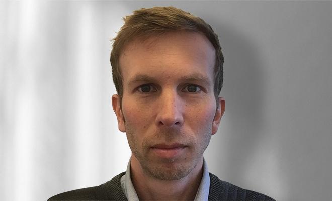 Close up photo of a man with short hair looking directly at the camera