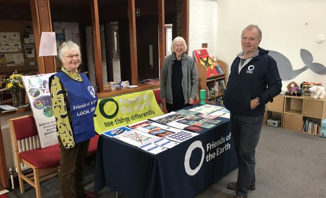A group of 3 people standing in front of their Friends of the Earth branded information stall