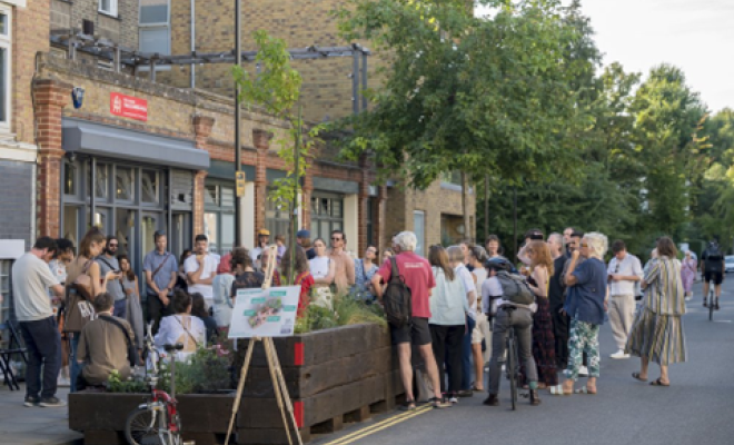 A crowd of people on a street by a large planter