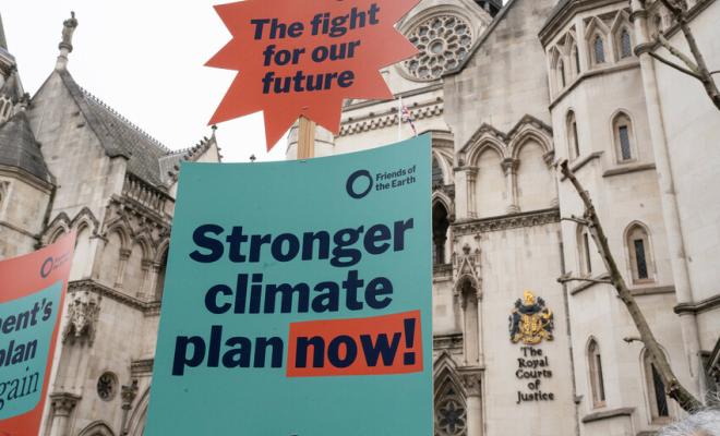 A protest banner which reads "Stronger climate plan now!" held outside of the Royal Courts of Justice