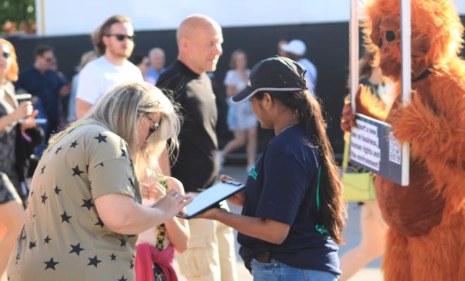 A person signing a petition with someone else dressed in an orangutan costume